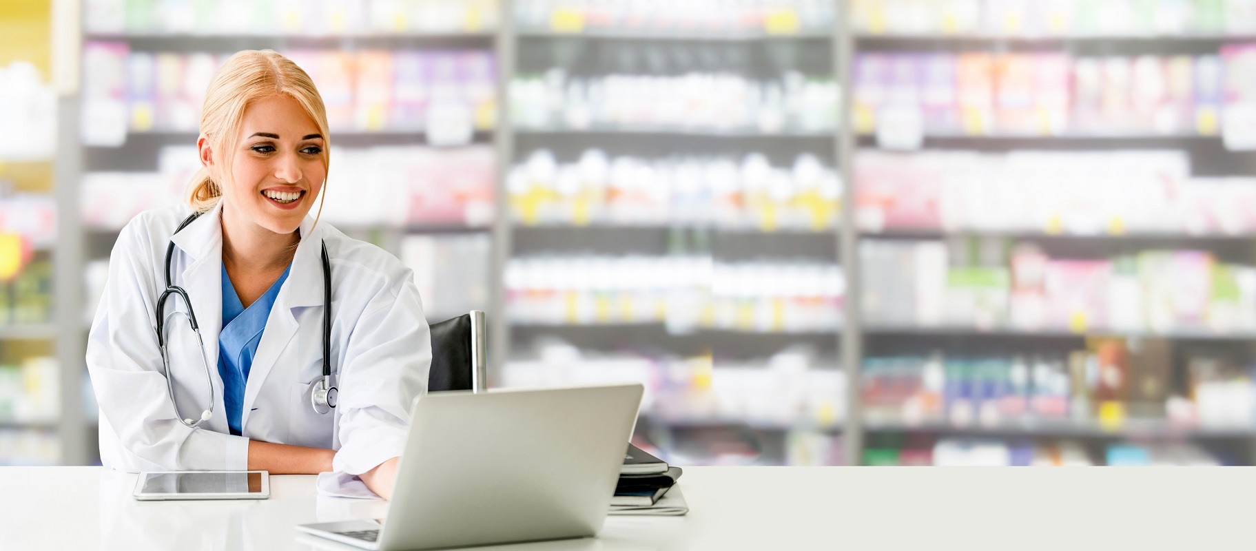 Pharmacist using laptop computer at pharmacy.